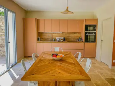 a kitchen with a wooden table with a bowl of fruit on it at Villa Lisette, un meublé de tourisme 3 étoiles au cœur de Goult in Goult