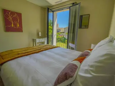a bedroom with a large white bed and a balcony at Villa Lisette, un meublé de tourisme 3 étoiles au cœur de Goult in Goult