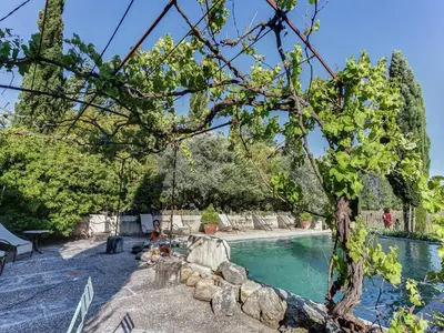 a swimming pool with a tree and a swing at Cottage in Oppède with Pool and Garden in Maubec