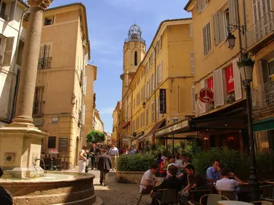 a group of people sitting in a street with a clock tower at Cottage in Oppède with Pool and Garden in Maubec