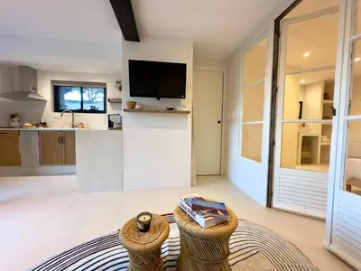a living room with a tv and a kitchen at Logement de Charme vue Luberon - Rez-de-chaussée de maison, Jardin & Piscine in La Tour-dʼAigues