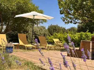 a group of chairs and an umbrella on a wooden deck at Logement de Charme vue Luberon - Rez-de-chaussée de maison, Jardin & Piscine in La Tour-dʼAigues