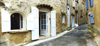 an alley with white doors on a stone building at Les studettes du Beffroi in Cucuron