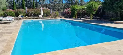 a blue swimming pool with chairs and trees at Moulin AURELIA - chambre La Coloniale in Pélissanne