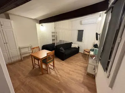 a living room with a black couch and a table at Studio Cosy hyper centre Aix in Aix-en-Provence