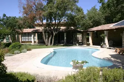 a swimming pool in front of a house at Villa La Raffinée, au coeur des garrigues du Luberon in Gordes
