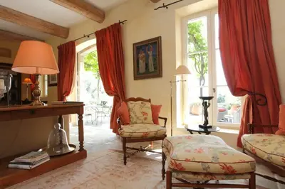 a living room with a bed and a chair and windows at Villa l'Écrin, piscine et 3 terrasses in Gordes