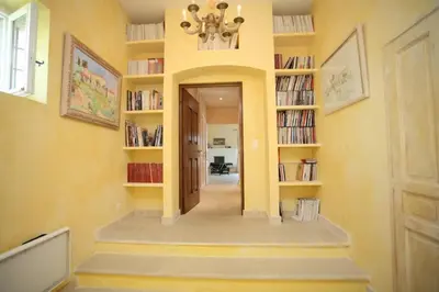 a hallway with yellow walls and bookshelves at Villa l'Écrin, piscine et 3 terrasses in Gordes