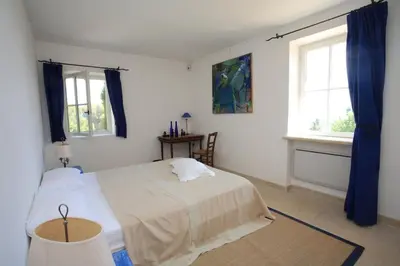 a bedroom with a bed and two windows at Villa l'Écrin, piscine et 3 terrasses in Gordes