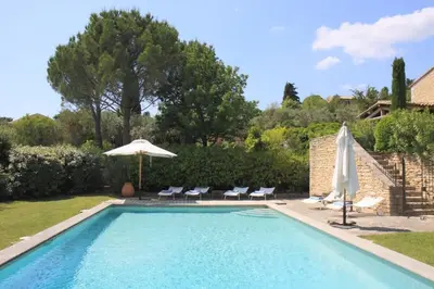 a swimming pool with chairs and an umbrella at Villa l'Écrin, piscine et 3 terrasses in Gordes