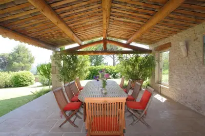 a patio with a table and chairs under a wooden ceiling at Villa l'Écrin, piscine et 3 terrasses in Gordes