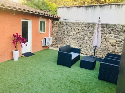 a patio with two chairs and an umbrella on the grass at Maisonnette T1 au calme à 1min à pied de la gare SNCF in Miramas
