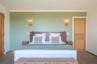 a bedroom with a large bed with two pillows at Le Mas Elaïa, votre havre familial avec piscine privée in Eyragues