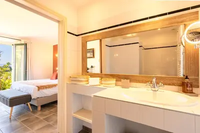 a bathroom with a sink and a bed and a mirror at Le Mas Elaïa, votre havre familial avec piscine privée in Eyragues
