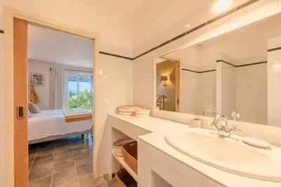 a bathroom with a sink and a mirror and a bedroom at Le Mas Elaïa, votre havre familial avec piscine privée in Eyragues
