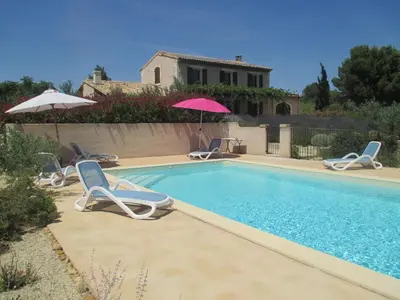 a pool with chairs and umbrellas next to a house at Villa avec piscine Saint Remy de Provence LS1-196 in Saint-Rémy-de-Provence