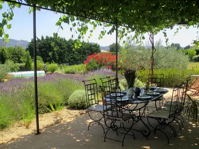 a table and chairs in a garden with flowers at Villa avec piscine Saint Remy de Provence LS1-196 in Saint-Rémy-de-Provence