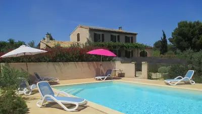 a swimming pool with chairs and an umbrella and a house at Villa avec piscine Saint Remy de Provence LS1-196 in Saint-Rémy-de-Provence