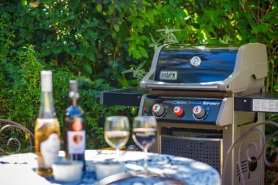 a grill and two glasses of wine on a table at Villa Le Bastidon by Villa Plus in Les Taillades