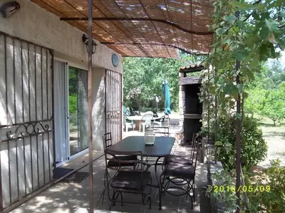 a patio with a table and chairs under a pergola at Le cabanon, 3 étoiles, sa piscine au pied du Luberon in Saint-Saturnin-les-Apt
