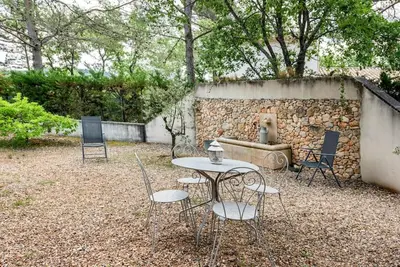 a table and chairs in front of a stone wall at Le cabanon, 3 étoiles, sa piscine au pied du Luberon in Saint-Saturnin-les-Apt