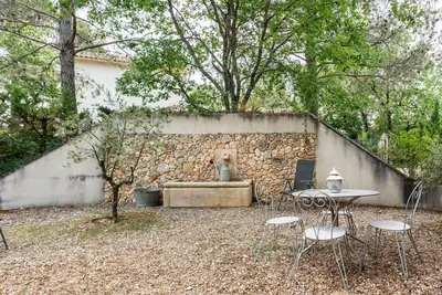 a patio with a table and chairs and a stone wall at Le cabanon, 3 étoiles, sa piscine au pied du Luberon in Saint-Saturnin-les-Apt