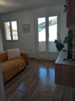 a living room with a couch and wooden floors at Studio entièrement rénové in Cavaillon