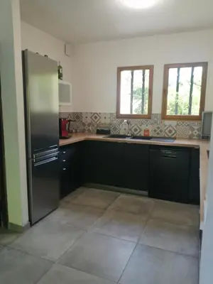 a kitchen with black cabinets and a stainless steel refrigerator at #Villa Théo# Grande villa avec piscine in Apt