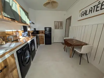 a kitchen with a washer and dryer and a table at La Galatée, Balnéo et Sauna privatifs in Saint-Saturnin-lès-Avignon