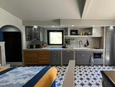 a kitchen with gray cabinets and a bed in a room at Maisonnette climatisée in Aix-en-Provence