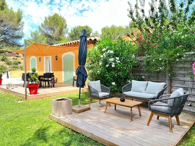 a patio with chairs and an umbrella on a wooden deck at The Maisonnette in the pines in Ventabren