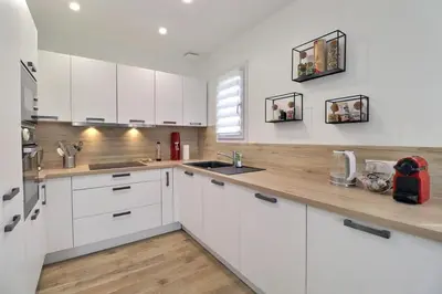a kitchen with white cabinets and a wooden counter top at The Maisonnette in the pines in Ventabren