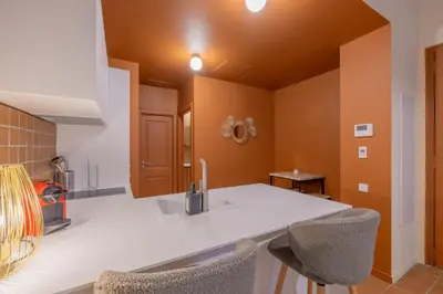 a kitchen with orange walls and a sink and chairs at Appartement Belle Lettre 1 in Aix-en-Provence