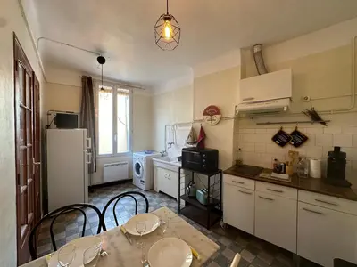 a kitchen with a table and chairs and a refrigerator at Chez Monique - Appartement T2 au cœur du centre ville historique - proche Mairie et Cardeurs in Aix-en-Provence