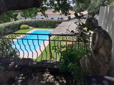 a fence with a swimming pool in a yard at Au pied du Luberon in Les Taillades
