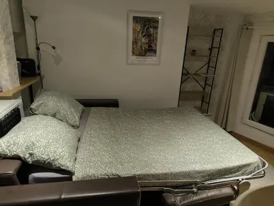 a bed in a room with a chair and a window at Le Nid plein centre in Salon-de-Provence