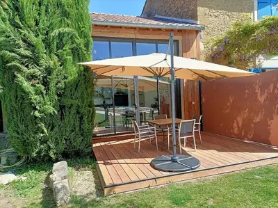 a wooden deck with a table and an umbrella at Superbe appartement neuf au cœur de la Provence. in Entraigues-sur-la-Sorgue