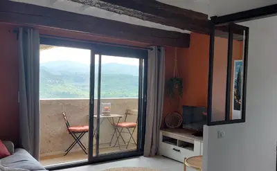 a living room with a sliding glass door to a balcony at Le Cosy Luberon - Viens in Viens
