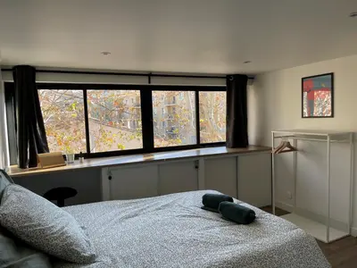 a bedroom with a bed in front of a window at L'Olivier - Joli duplex au cœur du centre ville à 2 pas de la Rotonde Mirabeau et des allées Provençales in Aix-en-Provence