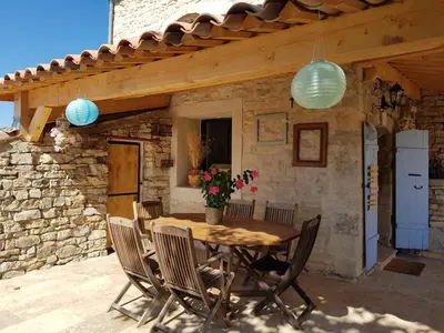 a patio with a wooden table and chairs at Maison en Luberon in Sainte-Croix-à-Lauze