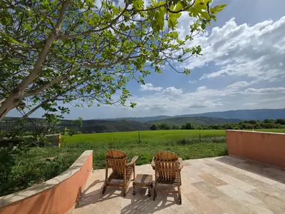 two chairs and a table on a patio with a view at Maison en Luberon in Sainte-Croix-à-Lauze