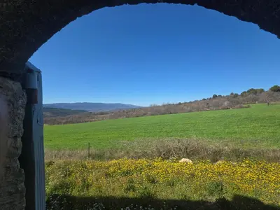 a view from a window of a field of grass and flowers at Maison en Luberon in Sainte-Croix-à-Lauze