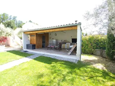 a covered patio with a table and a kitchen at L'escapade provençale in Lioux