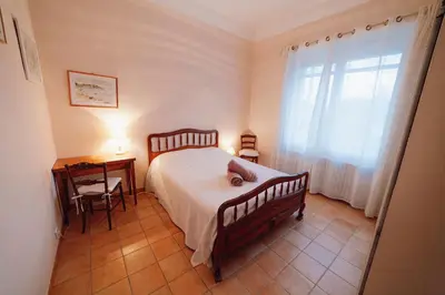 a bedroom with a bed and a desk and a window at Villa en Luberon, climatisé, Piscine, wifi et Parking gratuit in Bonnieux
