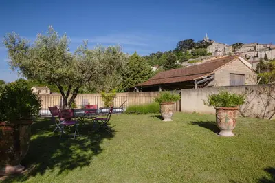 a yard with two chairs and a table and a fence at Villa en Luberon, climatisé, Piscine, wifi et Parking gratuit in Bonnieux