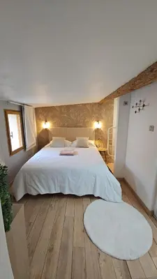 a bedroom with a large white bed and a wooden floor at Cocon Authentique de Roussillon in Roussillon