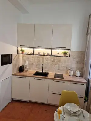 a kitchen with white cabinets and a sink and a table at Appartement Cosy Hyper Centre Climatisé - Rue Bédarrides in Aix-en-Provence