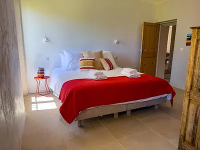 a bedroom with a large bed with a red blanket at La Magnanerie 1818 villa de prestige 5 étoiles Luberon in Saint-Saturnin-les-Apt