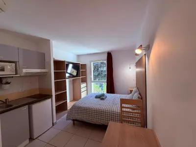 a small room with a bed and a kitchen at Le Clos d'Aix studio 105 parking in Aix-en-Provence