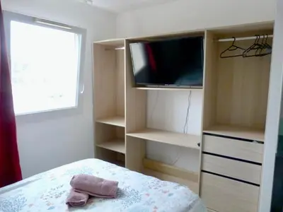 a bedroom with a bed and a tv and shelves at Le Clos d'Aix studio 208 parking in Aix-en-Provence